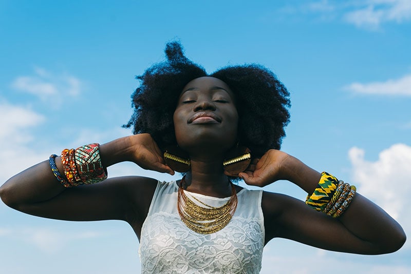 Dame met afro haar houdt haar nek vast terwijl ze lacht