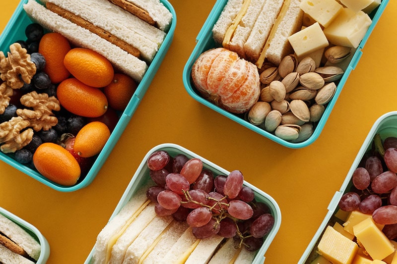 Flat lay foto eten in blauwe bakjes en gele achtergrond