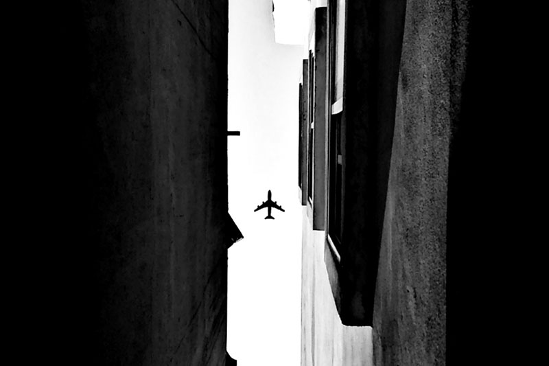 Vliegtuig in de lucht gekaderd door omhoog fotograferen in een steeg